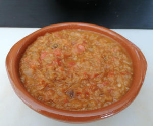 Pisto manchego tradicional servido en cazuela de barro con huevo frito