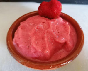 Helado de fresa cremoso servido en copa con fresas frescas